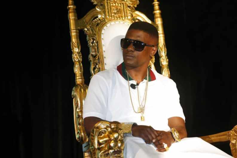 A person wearing sunglasses and a white robe sitting in a gold chairDescription automatically generated with low confidence