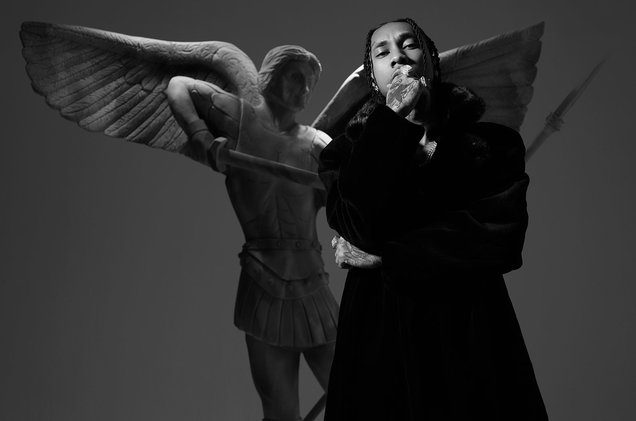 tyga rapper with angel statue in the background