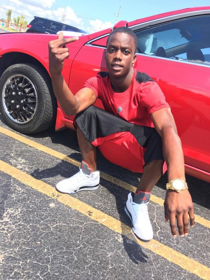 A person in a red shirt kneeling in front of a red car

Description automatically generated with medium confidence