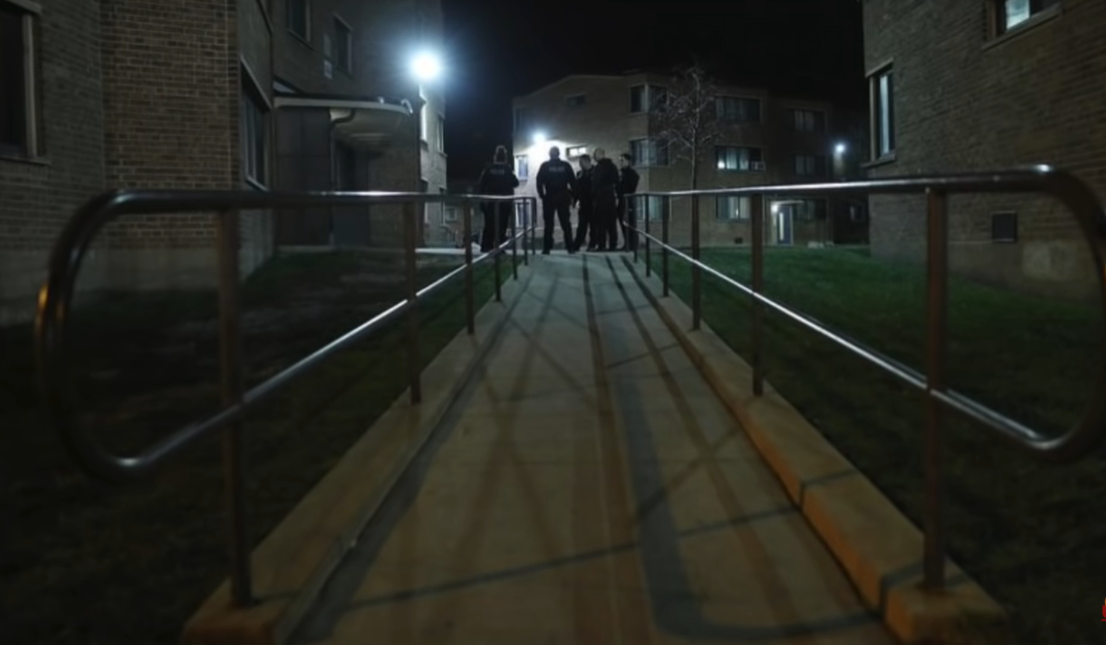 The Legacy Of T.Roy: The Chiraq Rambo 74 A group of people walking down a sidewalk at night
Description automatically generated with medium confidence