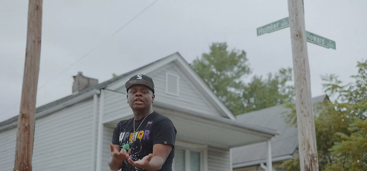 <strong>EST GEE: From Pro Athlete To Drug Kingpin To Rap Superstar</strong> 19 A person standing next to a street sign
Description automatically generated with medium confidence